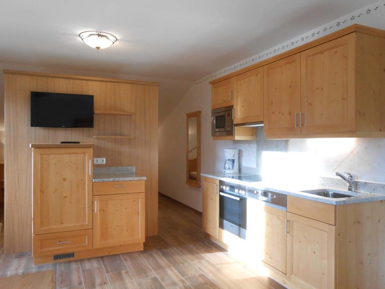 Moderne Küche im Gollehenhof mit Vollholzmöbeln und TV, ideal für Familienurlaub.