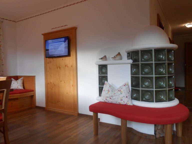 Gemütlicher Wohnbereich im Gollehenhof mit Kachelofen und rustichem Mobiliar.